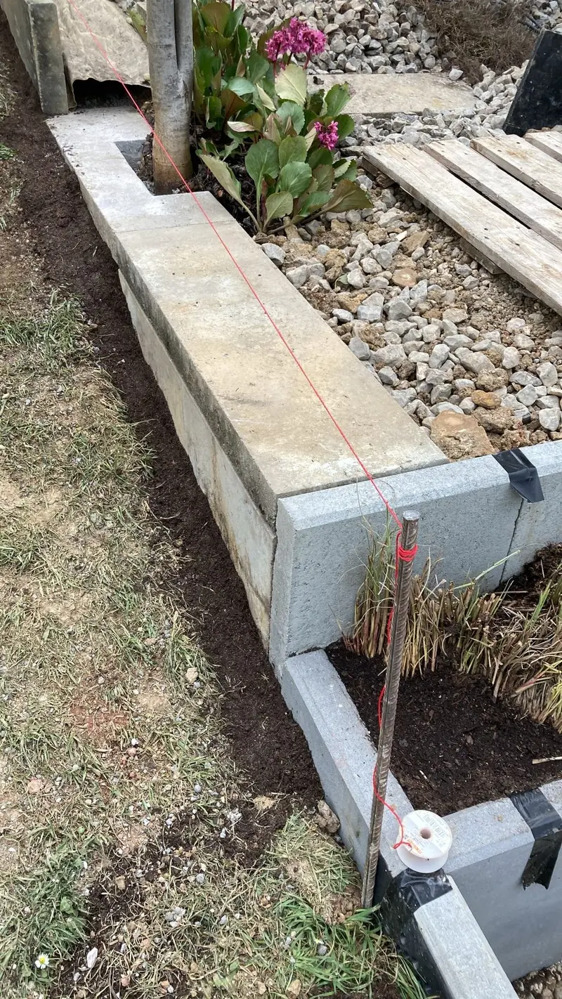 Stützmauer aus L-Steinen im Bau, ausgerichtet mit roter Richtschnur